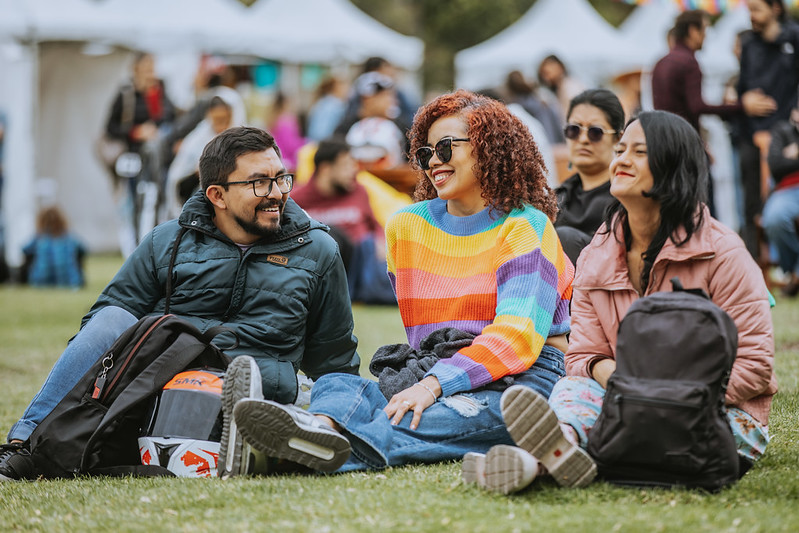 tres jóvenes disfrutando de un evento sentados y charlando entre ellos